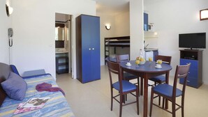 A hotel room with a bed, a dining table with chairs, a kitchenette, a TV, and a phone on the wall. - Nature Studio for 4 in Chames (Vallon-Pont-d'Arc)