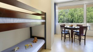 A bunk bed with a teddy bear and a toy camper, a dining table with chairs, and a window with a view of trees. - Nature Studio for 4 in Chames (Vallon-Pont-d'Arc)