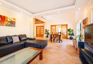 Ein modernes Wohnzimmer mit einer Couch, Couchtisch, Fernseher und einem Essbereich mit Stühlen und Tisch.