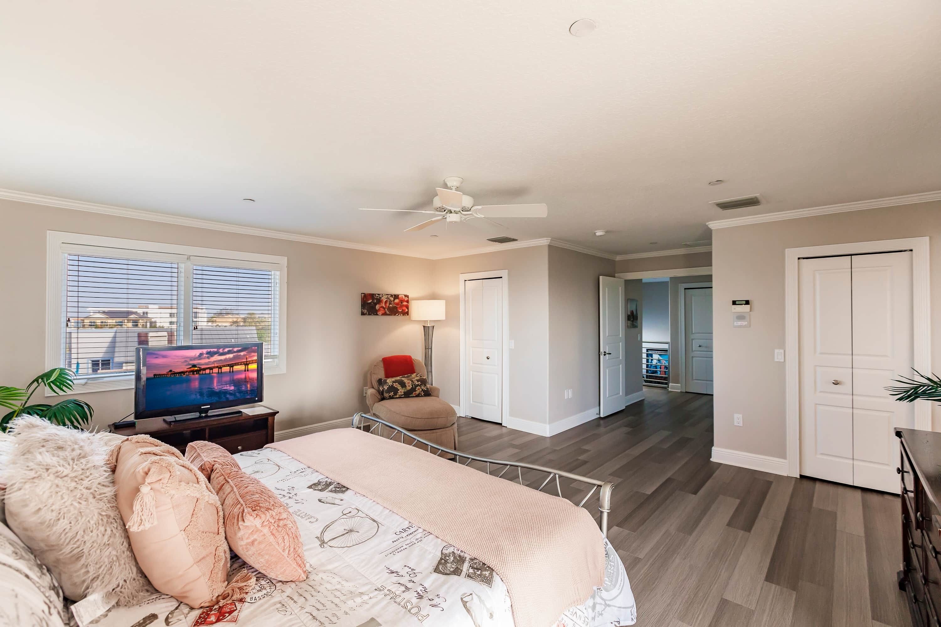 Un dormitorio con cama, televisor y ventana con persianas.