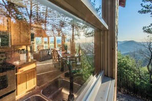 Eine moderne Küche mit großem Fenster und Blick auf bewaldetes Gelände.