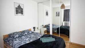 Ett sovrum med en säng, ett sängbord, en spegel och en hängande lampa.