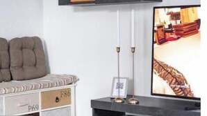 Ett modernt vardagsrum med en soffa, en tv och ett soffbord i glas.