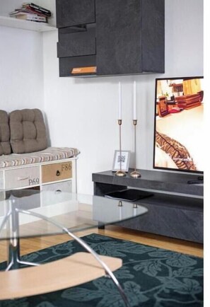 A modern living room with a sofa, a TV, and a glass coffee table. - Flat at Border Suisse - Modern apartment with terrace near Basel (Saint-Louis)