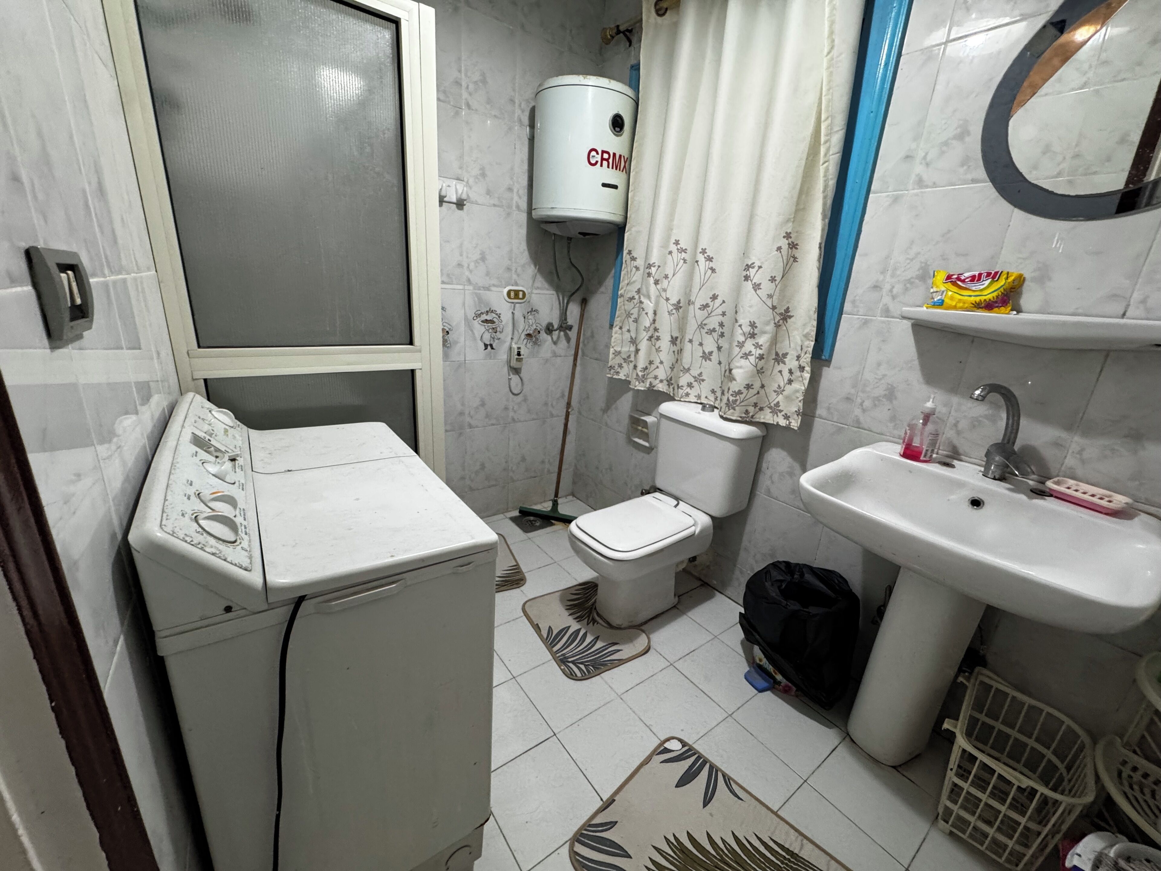 Une petite salle de bain équipée d’un lave-linge, de toilettes et d’un lavabo.