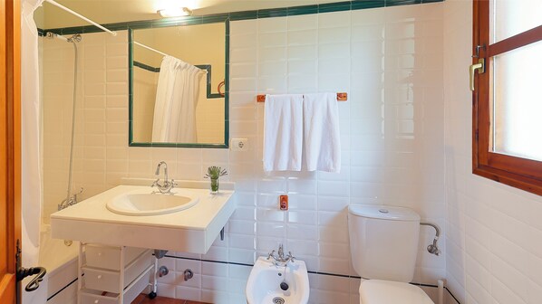 Un baño con lavamanos, espejo, toallero y retrete.
