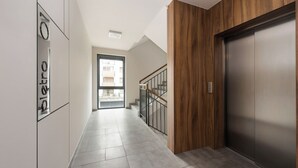 Un pasillo moderno con un panel de madera, una escalera con barandillas metálicas y una puerta con manija.