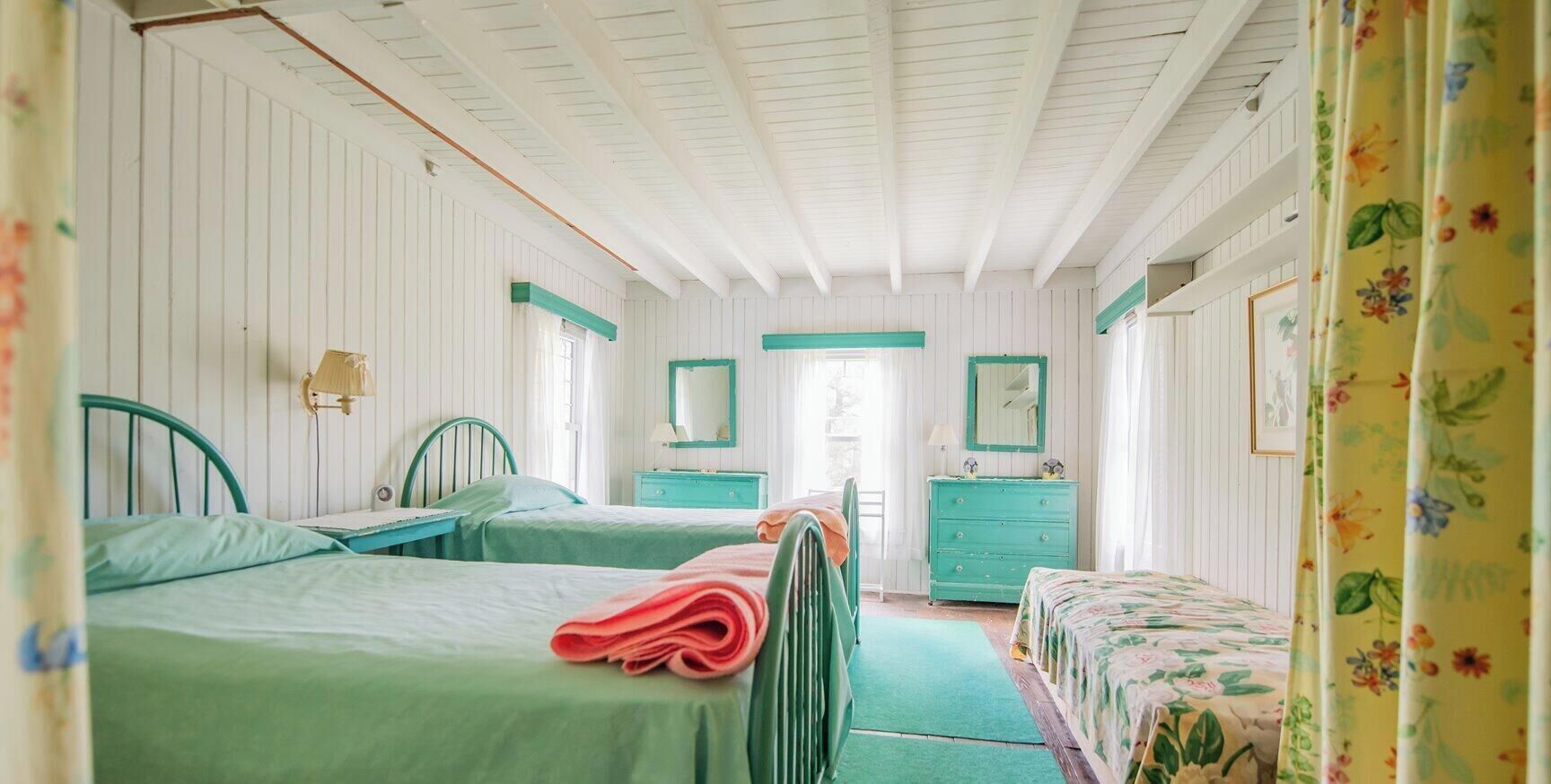 A room with two beds, a desk, a dresser, and a mirror.