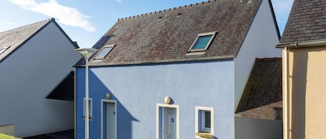 A row of houses with sloped roofs, a clear sky, and a street lamp.