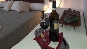 A hotel room with a bed, a bedside table with a bottle of wine, glasses, and a tray with grapes. - Casa di Alice (Barberino Tavarnelle)