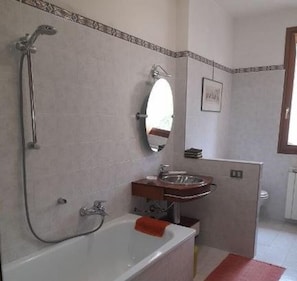 Une salle de bain avec une baignoire, un lavabo, une douche et un miroir.