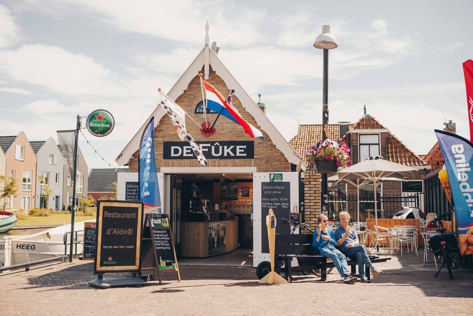 En restaurant, DEFÜKE, med et skilt, udendørs siddepladser og en gadelygte.