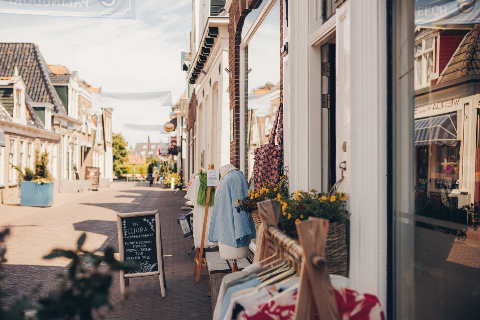 A street view with a shop window displaying clothing and a chalkboard sign.