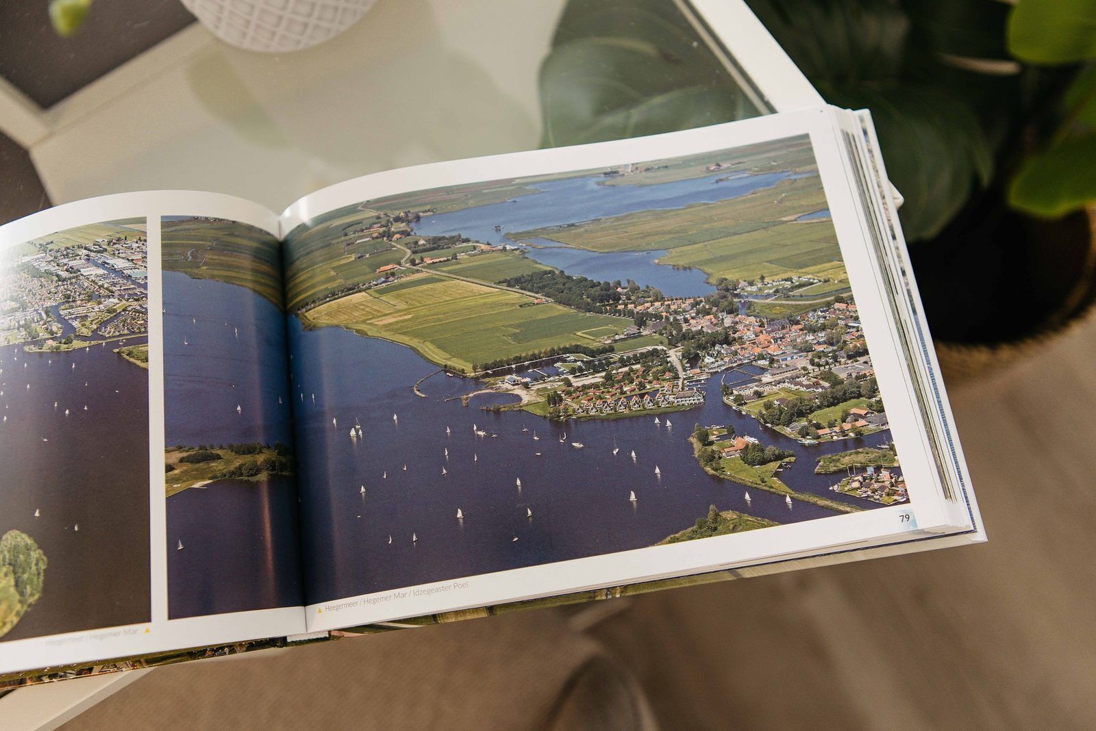 Um livro aberto com uma grande fotografia aérea de uma cidade costeira com barcos na água.