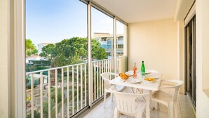 A balcony with a white table, chairs, and a bottle of water.