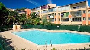 A swimming pool surrounded by a fence, with a multi-story building in the background.