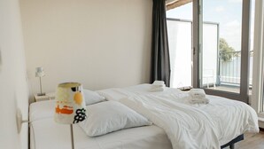 A hotel room with a bed, a nightstand, a lamp, and a window with curtains. - Parc Pharshoeke - Herenhuis geschakeld | 6p (Heeg)