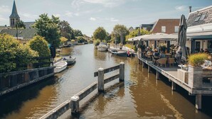 A canal with boats, a church, and a riverside café. - Parc Pharshoeke - Herenhuis geschakeld | 6p (Heeg)