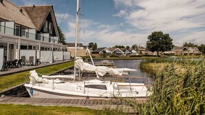 A waterfront property with a canal, a sailboat, and a building with a thatched roof. - Parc Pharshoeke - Herenhuis geschakeld | 6p (Heeg)