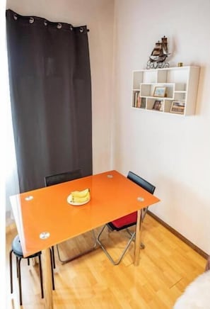 A room with a dining table, chairs, a curtain, a white shelf with items, and a small ship decoration. - Harmony Appart - Confort Moderne between France & Switzerland in Saint-Louis (Saint-Louis)