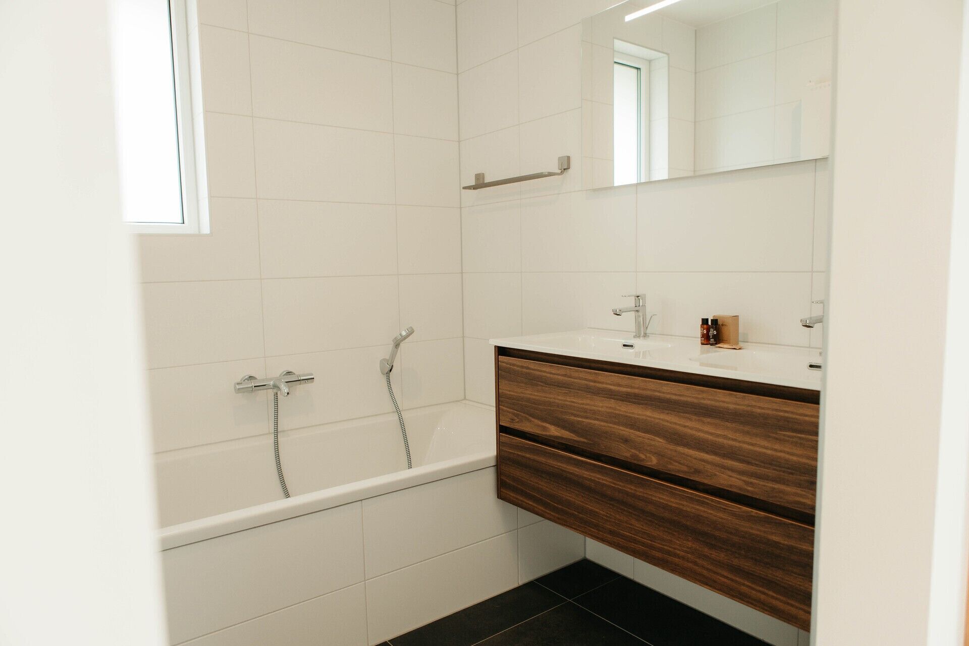 A modern bathroom with a bathtub, a vanity with a mirror, and a towel rack.