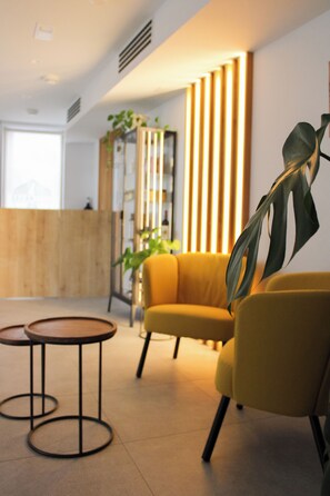 A modern interior with a reception desk, a yellow sofa, and a round table.