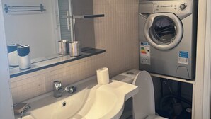 Ein Badezimmer mit Waschbecken, Toilette und Waschmaschine.