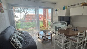 Ein modernes Wohnzimmer mit einer Couch, einem Glastisch und einem Essbereich mit Stühlen.
