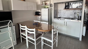 Eine kleine Küche mit weißen Schränken, einem Holzespeisetisch und einem Kühlschrank.