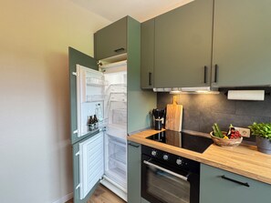 Eine moderne Küche mit integriertem Kühlschrank, Backofen und einer Holz Arbeitsplatte.