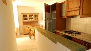 Une cuisine avec des armoires en bois, un plan de travail, un réfrigérateur et une cuisinière.