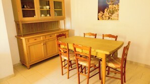 Un coin repas avec une table et des chaises en bois, un buffet en bois doté de portes en verre et un tableau encadré accroché au mur.