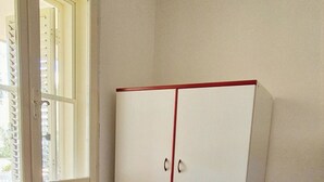 Une pièce avec une armoire blanche, une fenêtre et un sol carrelé.