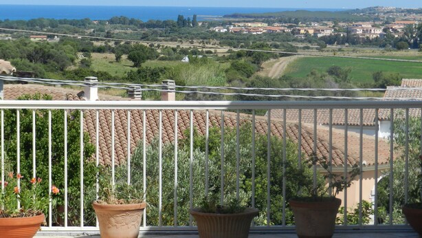 Un balcon offrant une vue sur un paysage côtier, avec des maisons et de la végétation.
