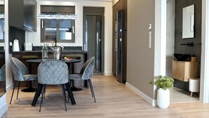 A modern kitchen with a dining area, featuring a black refrigerator, a built-in oven, and a dining table with four chairs. - Alimos Escape 2 (Alimos)