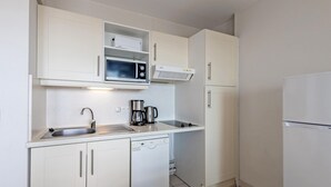 A compact kitchen with white cabinets, a microwave, a coffee maker, a dishwasher, and a refrigerator. - 6-guest Flat Near Coastal Path (Plougonvelin)