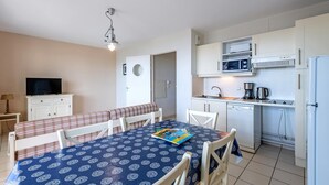A compact living space with a dining area, kitchenette, and a television. - 6-guest Flat Near Coastal Path (Plougonvelin)