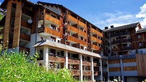 A multi-story hotel with balconies, a covered outdoor area, and a garden with various plants. - Rental for 10 Near Orcieres-merlette Slopes (Orcieres)