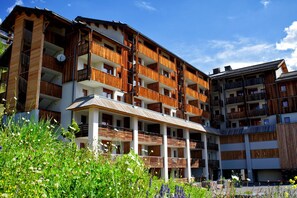 A multi-story hotel with balconies, a covered outdoor area, and a garden with various plants. - Rental for 10 Near Orcieres-merlette Slopes (Orcieres)