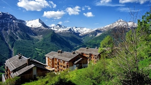 A mountain village with wooden buildings, a valley, and snow-capped peaks. - Rental for 10 Near Orcieres-merlette Slopes (Orcieres)