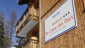A wooden building with a balcony and a sign indicating 'Residence Au Coeur des Ours' with a website address. - Spacious Alpine Retreat for Groups (Les Deux Alpes)
