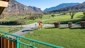 A view from a balcony overlooking a rural landscape with mountains, a road, and a small yellow structure. - Spacious Alpine Retreat for Groups (Les Deux Alpes)