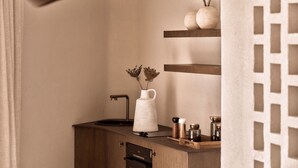 Une cuisine avec un évier, un pichet blanc et un vase contenant des fleurs séchées, le tout posé sur un comptoir en bois.