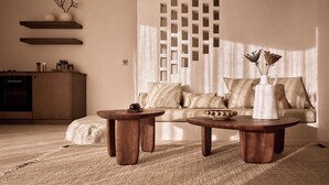 Un salon moderne avec une table basse en bois, un canapé avec des coussins et un panneau décoratif mural.