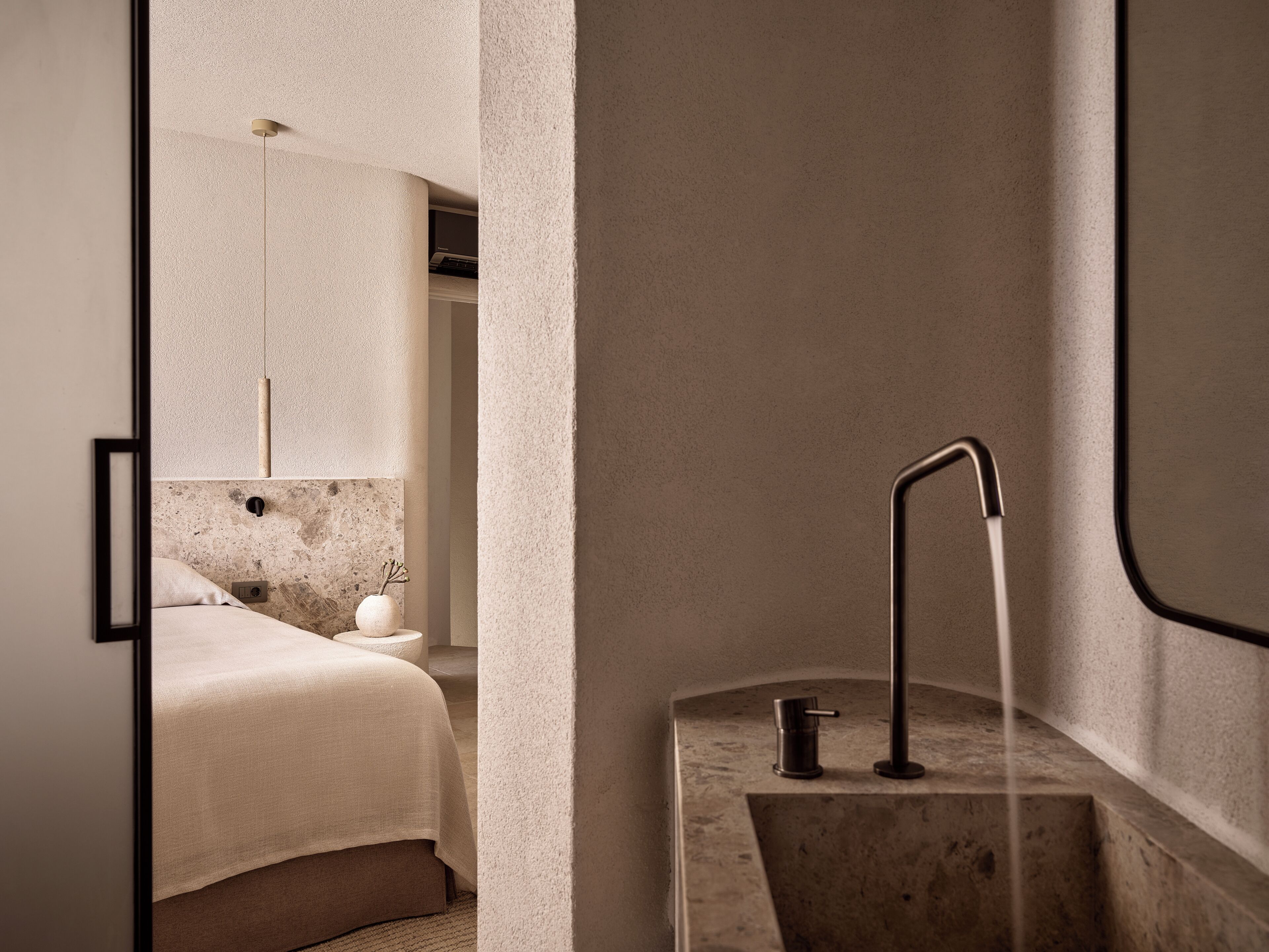 Ein modernes Badezimmer mit minimalistischem Design, ausgestattet mit einem Waschbecken und einem gebogenen Wasserhahn, einer Marmorarbeitsplatte sowie einer sichtbaren Duschfläche.