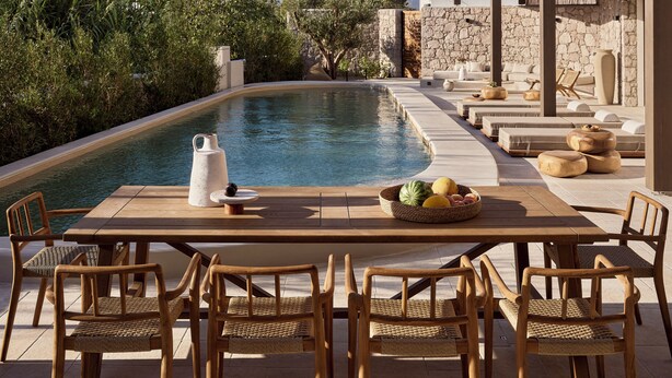 Un espace aménagé au bord de la piscine, avec une table, des chaises et un mur en pierre.