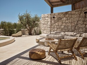 An outdoor seating area with stone walls, a sofa, and wicker chairs.