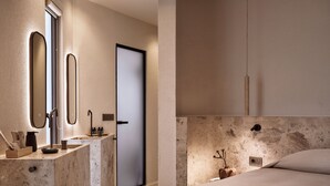 Une salle de bain moderne avec un meuble-lavabo en marbre, un évier et un miroir.