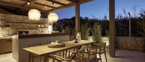An outdoor dining area with a stone wall, wooden table, and chairs.