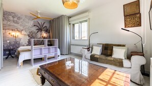 Ein modernes Wohnzimmer mit Sofa, Couchtisch, Deckenventilator und Wandlampe.